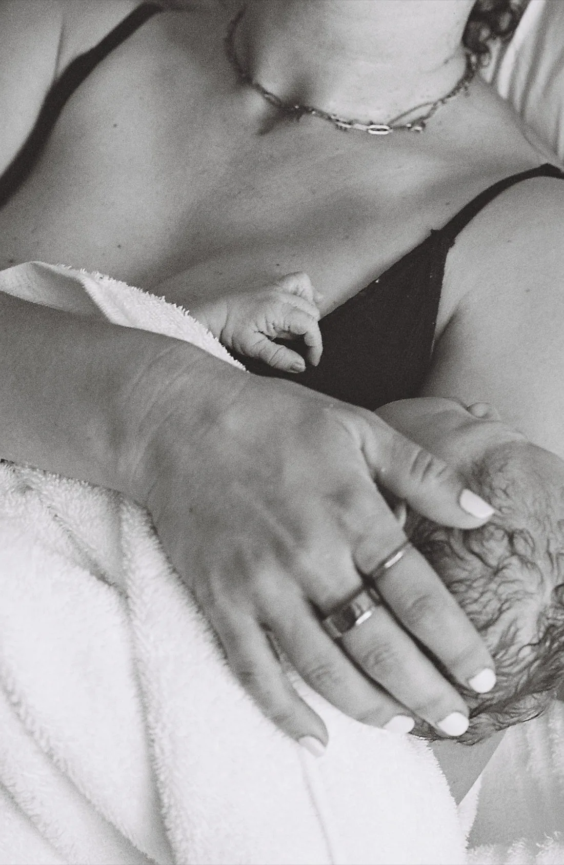 A newborn’s hand resting on their mother